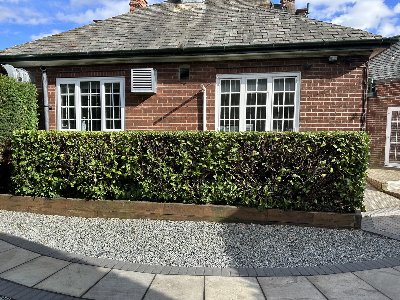 Low hedge cut square in front of a brick property