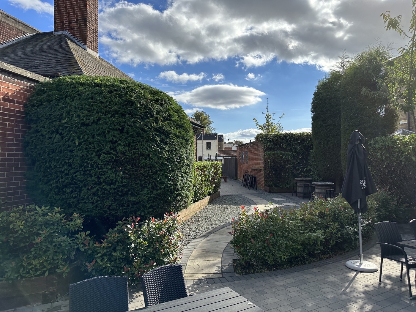 Maintained hedging, shrub beds and paving in a courtyard seating area